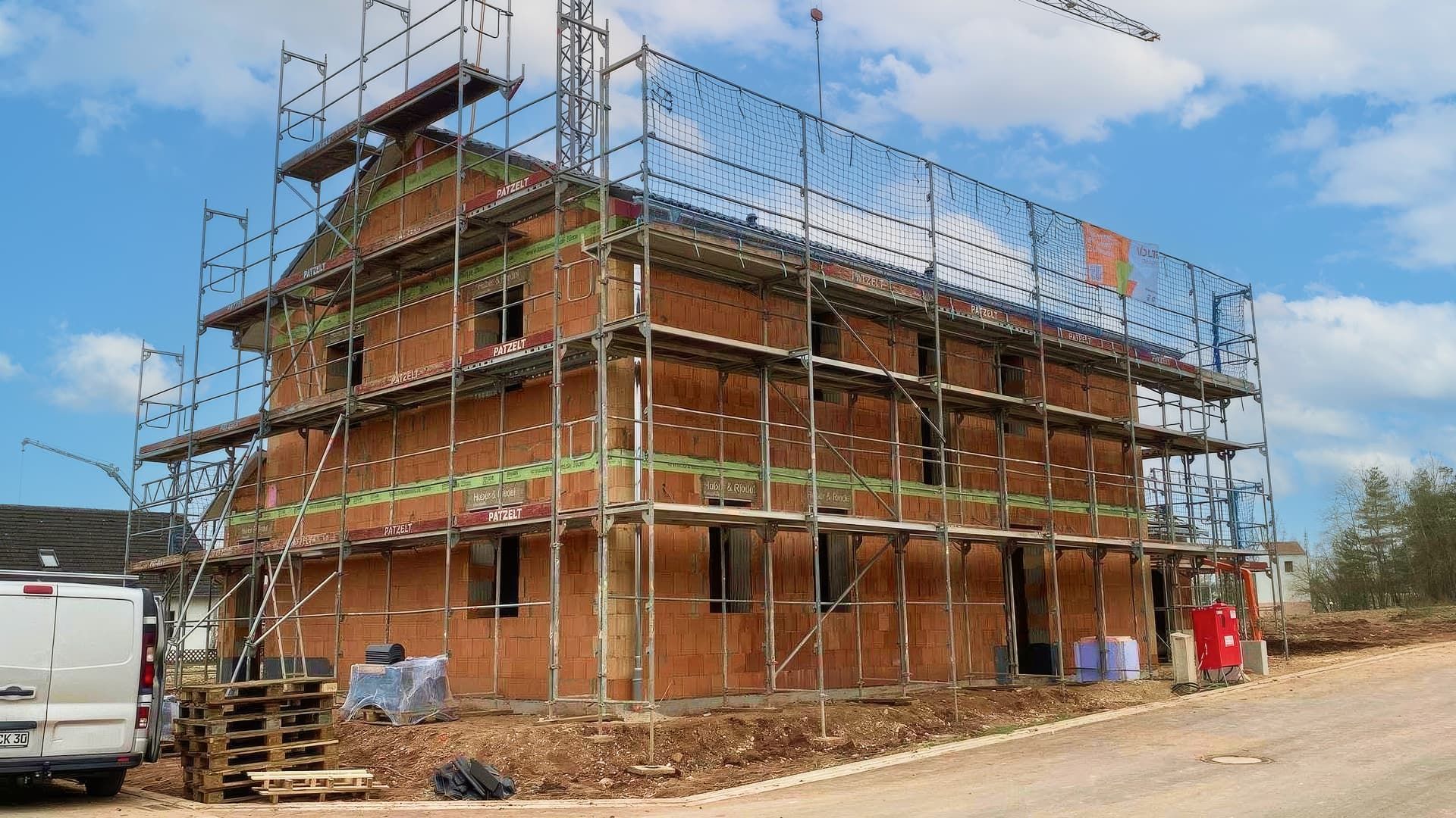 Rohbau eines mehrstöckigen Wohnhauses mit Gerüst und Schutznetzen im Landkreis Ansbach
